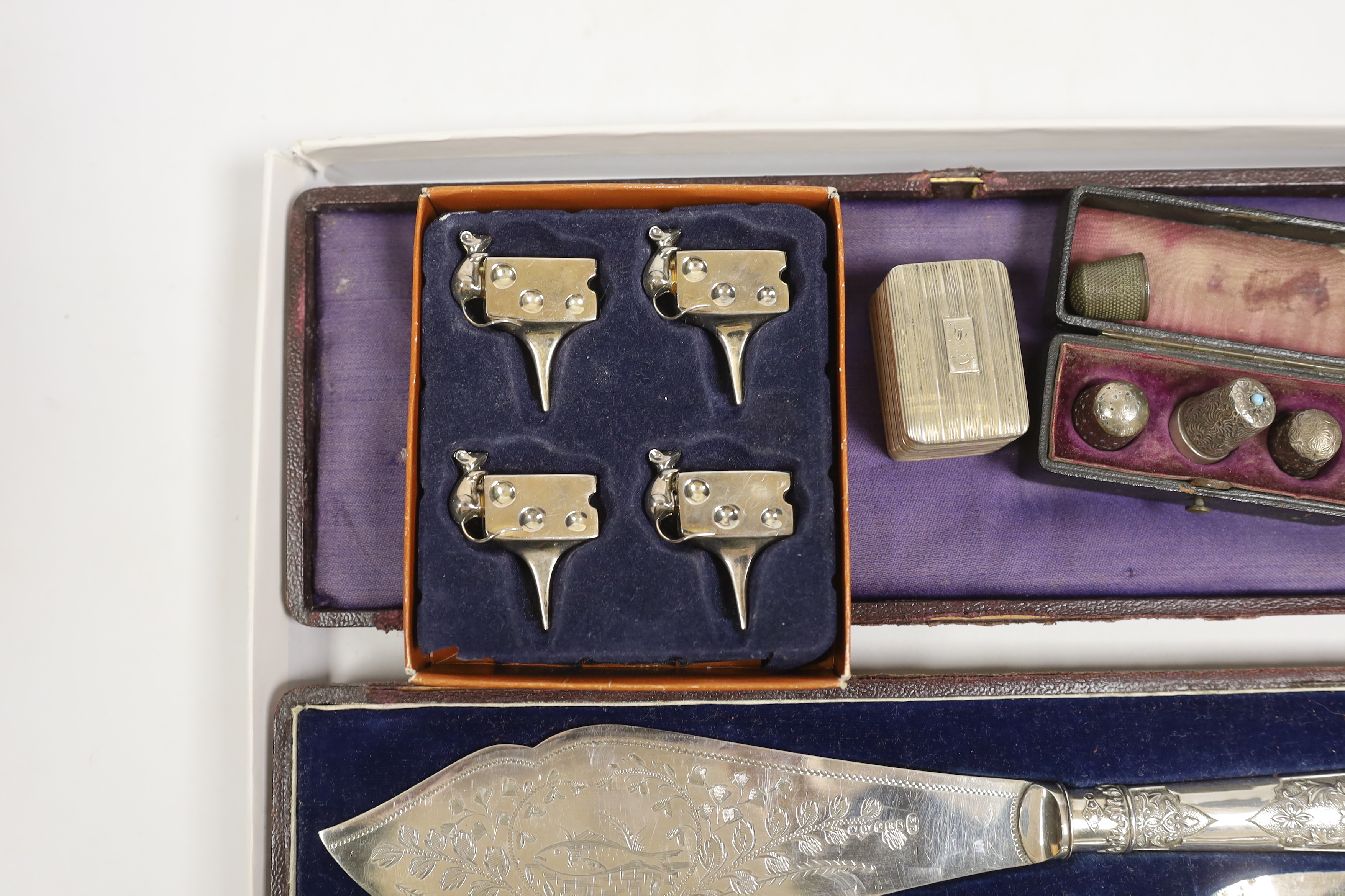 A George III silver nutmeg grater(lacking rasp), Birmingham, 1816, 42mm, together with four assorted thimbles, two silver, a based pair of silver plated fish servers and a set of four metal cheese card holders.